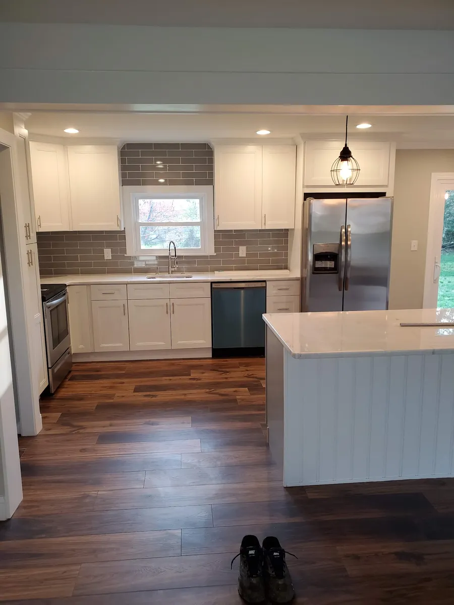 Finished kitchen remodel with island, white cabinetry and hardwood floors